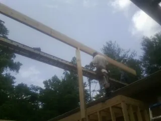 Carpenter setting a ridge beam over a new addition frame — Ice Dam Removal by Roofing Brothers in Fayetteville