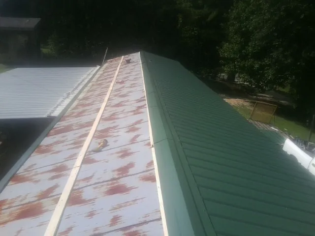 Old rusted panels beside newly installed green metal roofing — Wind Damage Roof Repair by Roofing Brothers in Fayetteville