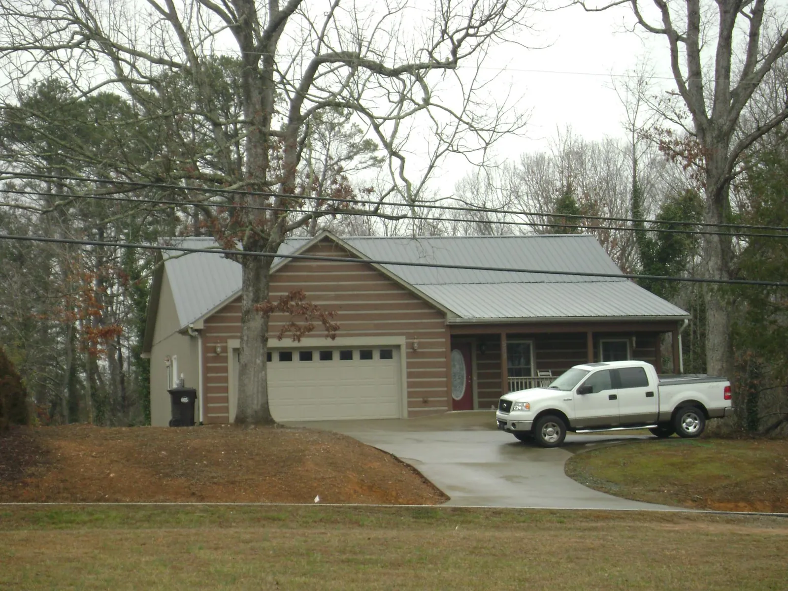 Gray metal roof on a log sided house with an attached two car garage in Fayetteville